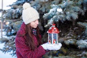 ung flicka med röd jul lykta i de snö foto