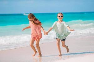 förtjusande liten flickor ha roligt tillsammans på vit tropisk strand foto