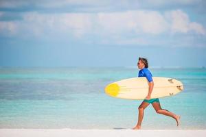 ung surfa man på vit strand med gul surfingbräda foto