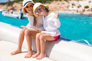 liten söt flickor njuter segling på båt i de öppen hav foto