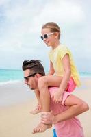 Lycklig pappa och hans liten dotter på tropisk strand har roligt foto