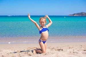 förtjusande liten flicka framställning hjul på tropisk vit sandig strand foto