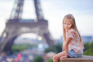 söt liten flicka bakgrund de eiffel torn under sommar semester i paris foto