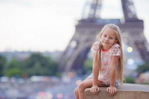 förtjusande liten flicka bakgrund de eiffel torn under sommar semester i paris foto