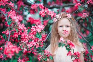 förtjusande liten flicka i en blommande vår äpple trädgård foto