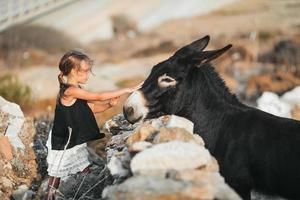 liten flicka med åsna på de ö av mykonos foto