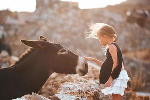 liten flicka med åsna på de ö av mykonos foto