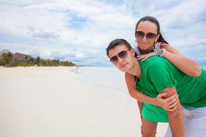 Lycklig ung par ha roligt på exotisk strand ser på kamera foto