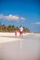 ung far och hans förtjusande liten dotter ha roligt på strand foto