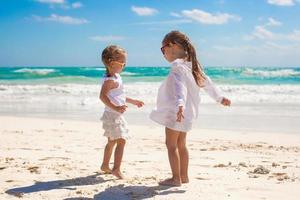 två liten systrar i vit kläder ha roligt på tropisk mexico strand foto
