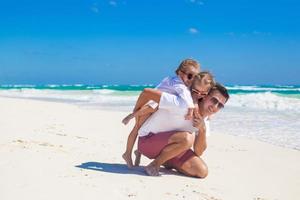 ung Lycklig far och liten döttrar har roligt på vit strand i solig dag foto