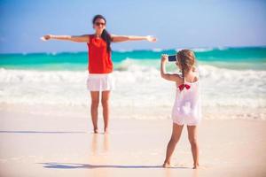 liten flicka fotografier henne mor på de strand foto