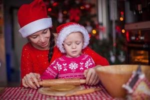 liten flicka med ung mor bakning jul pepparkaka småkakor tillsammans foto