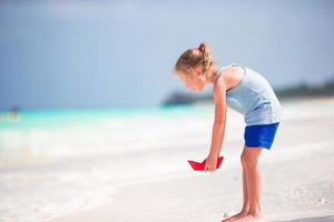 förtjusande liten flicka under strand semester har roligt i grund vatten foto