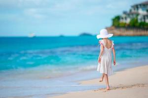 skön liten flicka i klänning på strand har roligt. foto