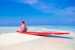 förtjusande liten flicka i röd santa hatt på surfingbräda under tropisk semester foto