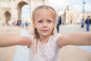 förtjusande liten flicka tar selfie med mobil telefon utomhus i paris foto