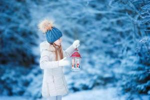 förtjusande liten flicka med ficklampa och ljus i vinter- på jul utomhus foto