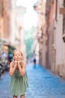 förtjusande Lycklig liten flicka utomhus i europeisk stad. porträtt av caucasian unge njut av sommar semester i rom foto