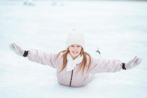 bedårande liten flicka åka skridskor på isbanan foto