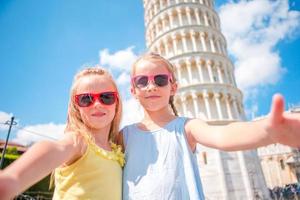 liten turister flickor tar selfie bakgrund de lutande torn i pisa, Italien. Foto handla om europeisk semester