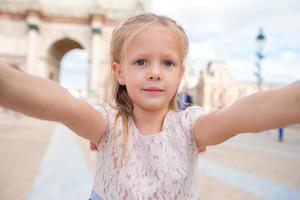 förtjusande liten flicka tar selfie med mobil telefon utomhus i paris foto