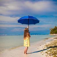 liten flicka med paraply på exotisk strand foto