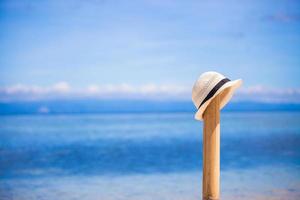 sugrör hatt på trä- staket på de vit sandig strand foto