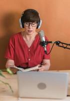 mogna kvinna framställning podcast inspelning för henne uppkopplad show. attraktiv företag kvinna använder sig av hörlurar främre av mikrofon för en radio utsända foto