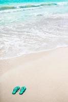 sommar mynta flip flops med solglasögon på vit strand foto