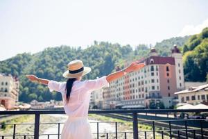 Lycklig flicka på hatt på de vägbank av en berg flod i en europeisk stad. foto