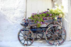 charmig dekorativ vagn med blommor på de gata i by av emporio på Kykladerna, grekland foto
