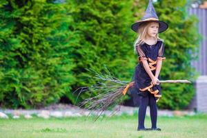 förtjusande liten flicka bär häxa kostym på halloween på höst dag. lura eller behandla. foto