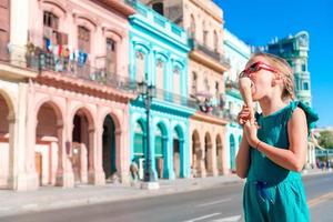 förtjusande liten flicka äter glass i populär område i gammal Havanna, kuba. porträtt av sötaste unge utomhus på en gata av havana foto