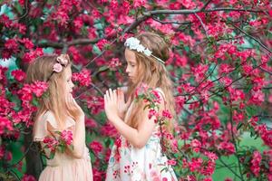 förtjusande liten flickor i blomning äpple träd trädgård på vår dag foto