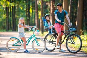 Lycklig familj cykling utomhus på de parkera foto