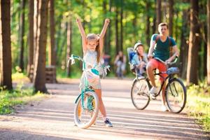 Lycklig familj cykling utomhus på de parkera foto