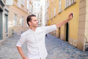 man turist med en stad Karta och ryggsäck i Europa gata. caucasian pojke ser med Karta av europeisk stad. foto