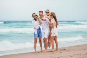 familj av ung förälder och två barn leende och njut av tid tillsammans på de strand semester foto