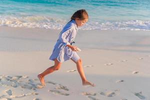 liten flicka på vit strand på solnedgång foto