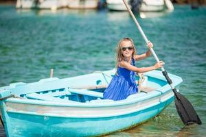 liten flicka i blå båt i de hav bukt i grekland foto