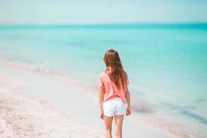 bedårande liten flicka ha kul på den tropiska stranden under semestern foto