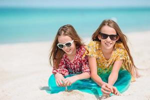 liten Lycklig rolig flickor ha en massa av roligt på tropisk strand spelar tillsammans. foto
