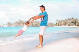 liten flicka och Lycklig pappa har roligt under strand semester foto