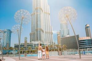 Lycklig familj gående i dubai med burj khalifa skyskrapa i de bakgrund. foto