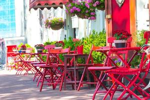 röd tabeller och stolar på en trottoar Kafé på europeisk stad foto