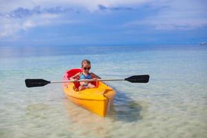 liten förtjusande flicka Kajakpaddling i de klar blå hav foto