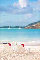 närbild santa hatt på stol på tropisk vit strand foto