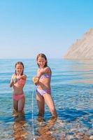 liten flickor har roligt på tropisk strand under sommar semester spelar tillsammans foto