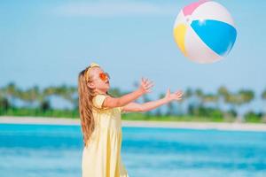 liten bedårande flicka som leker på stranden med boll foto